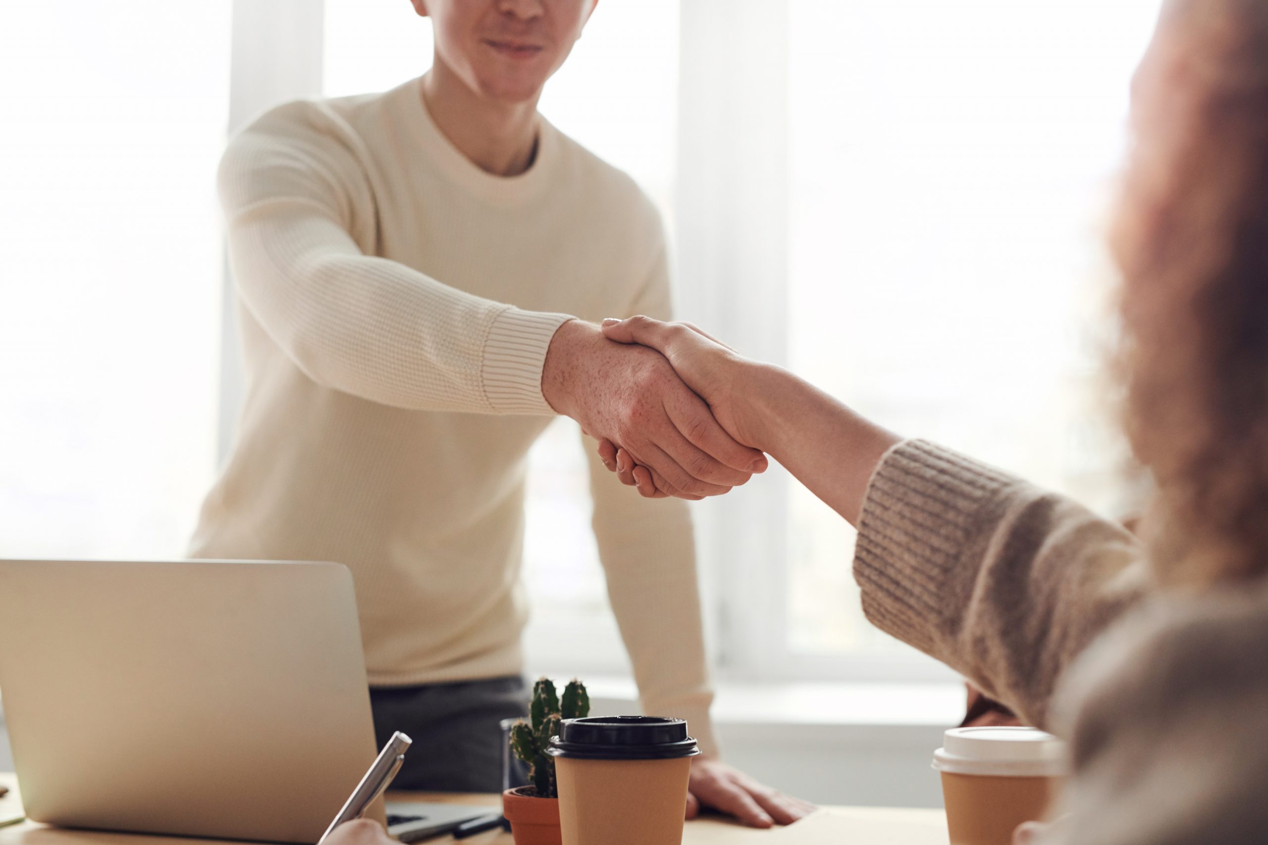 Man standing and shaking a woman's hand across a table